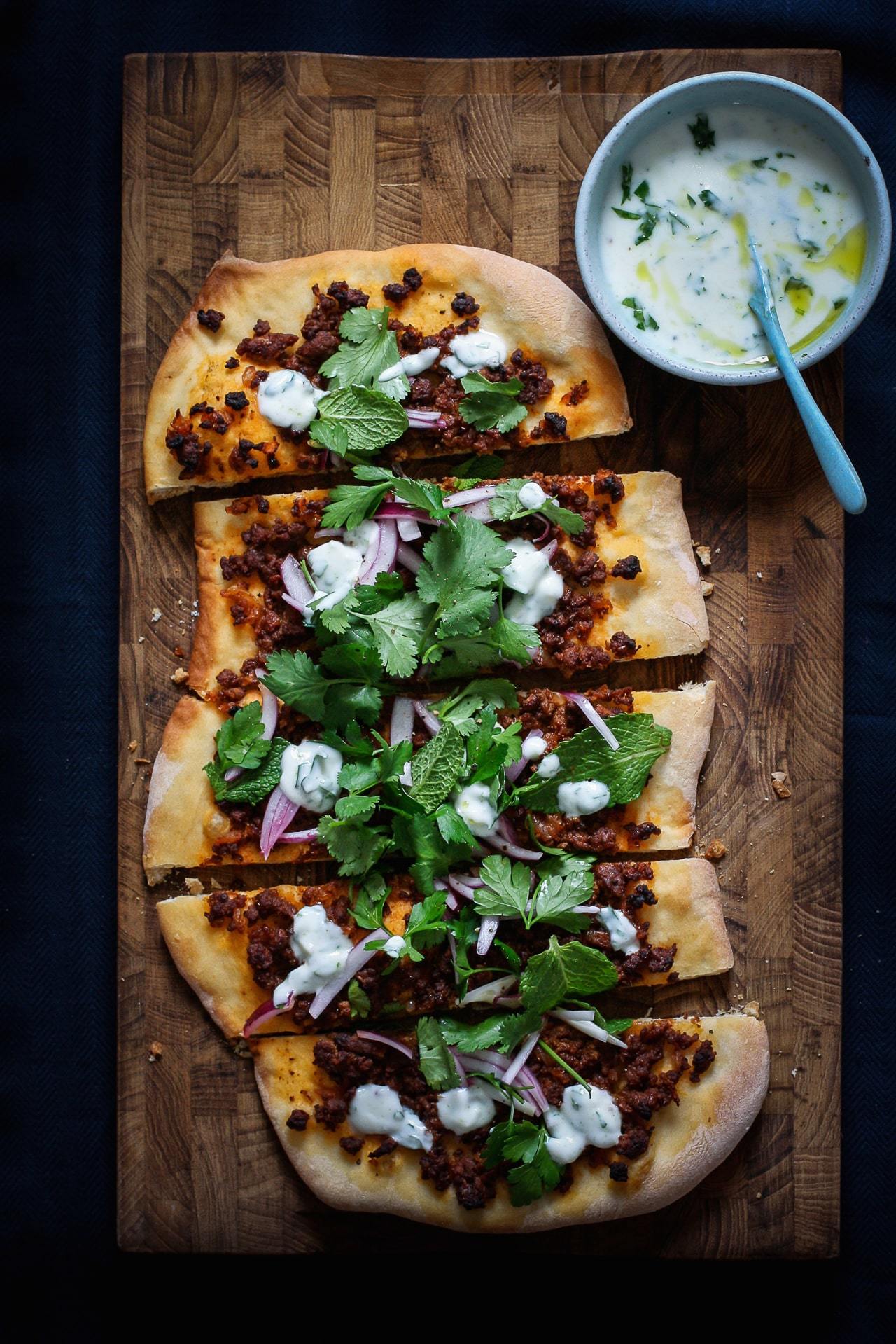 mellemøstlig pizza med sprød bund med krydret lam, rødløg og urter med yoghurtdressing